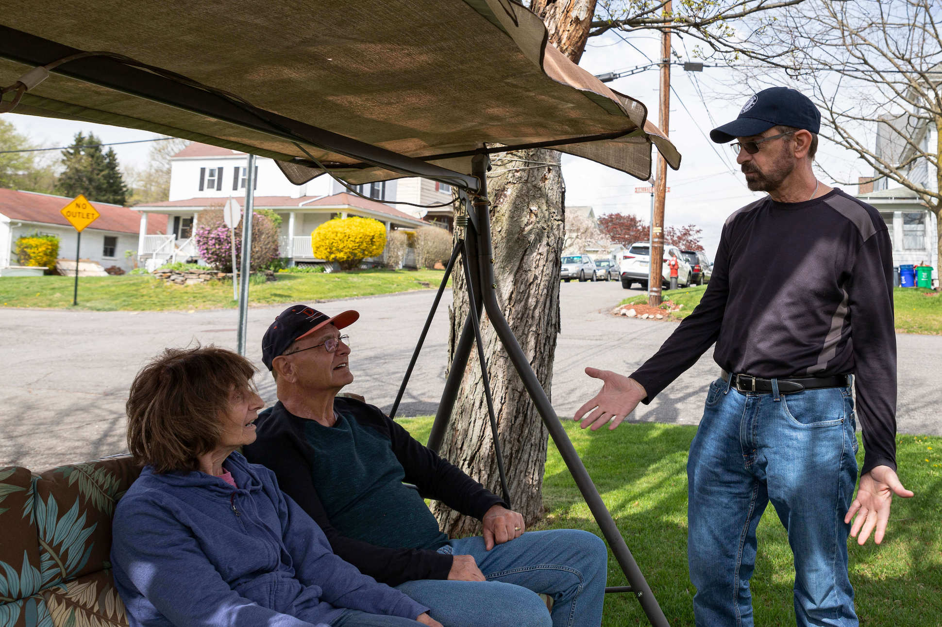 Mike Fedorka talking to two neighbors who are sitting on their swing in front of their house in Lackawanna County while knocking doors for his campaign for county commission.